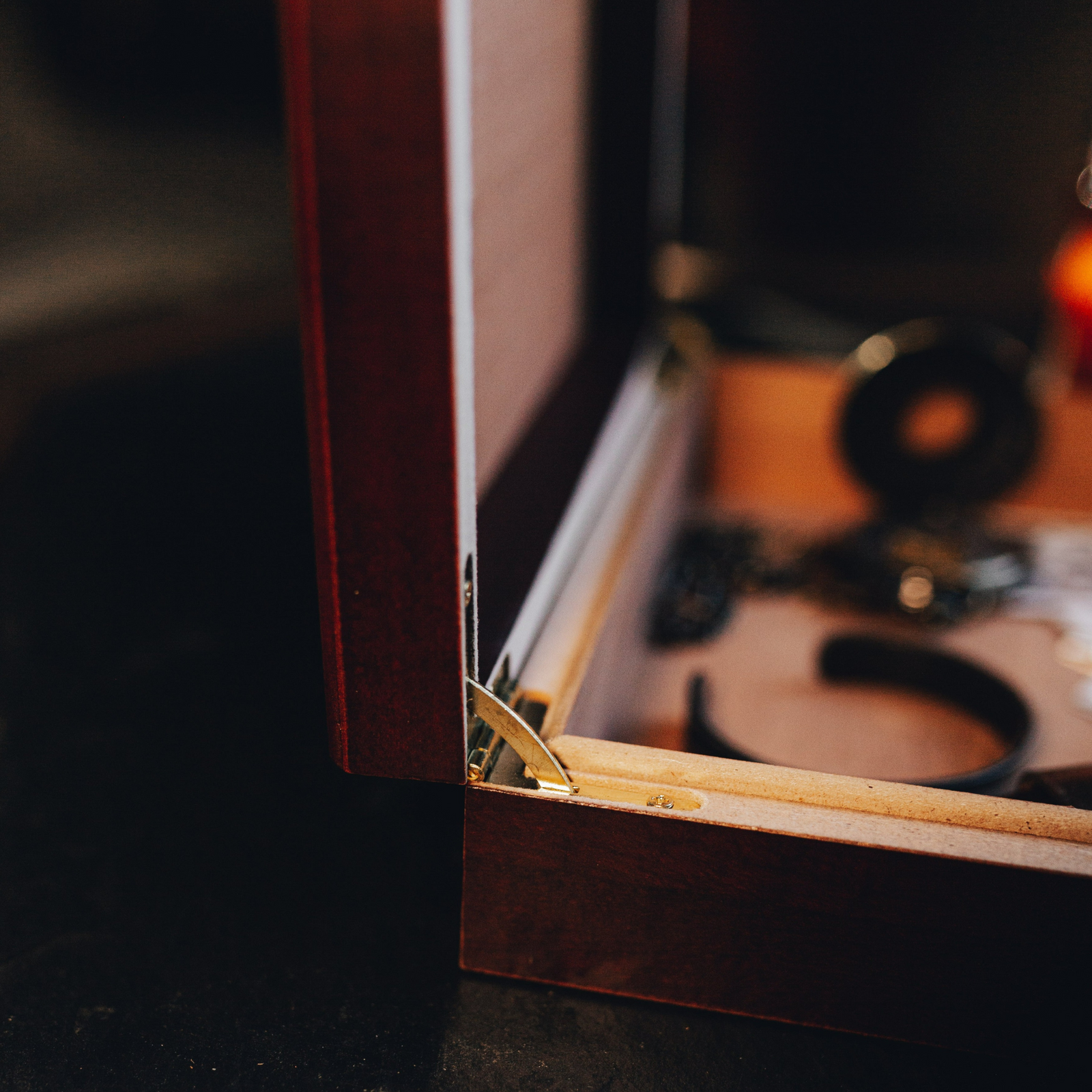 Close-up of the cherry wooden keepsake box corner showing the brass hinge and Spanish cedar interior