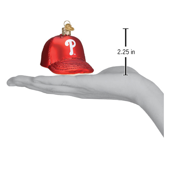 Red glass baseball cap ornament with white "P" logo displayed in palm of hand, showing 2.25-inch height measurement