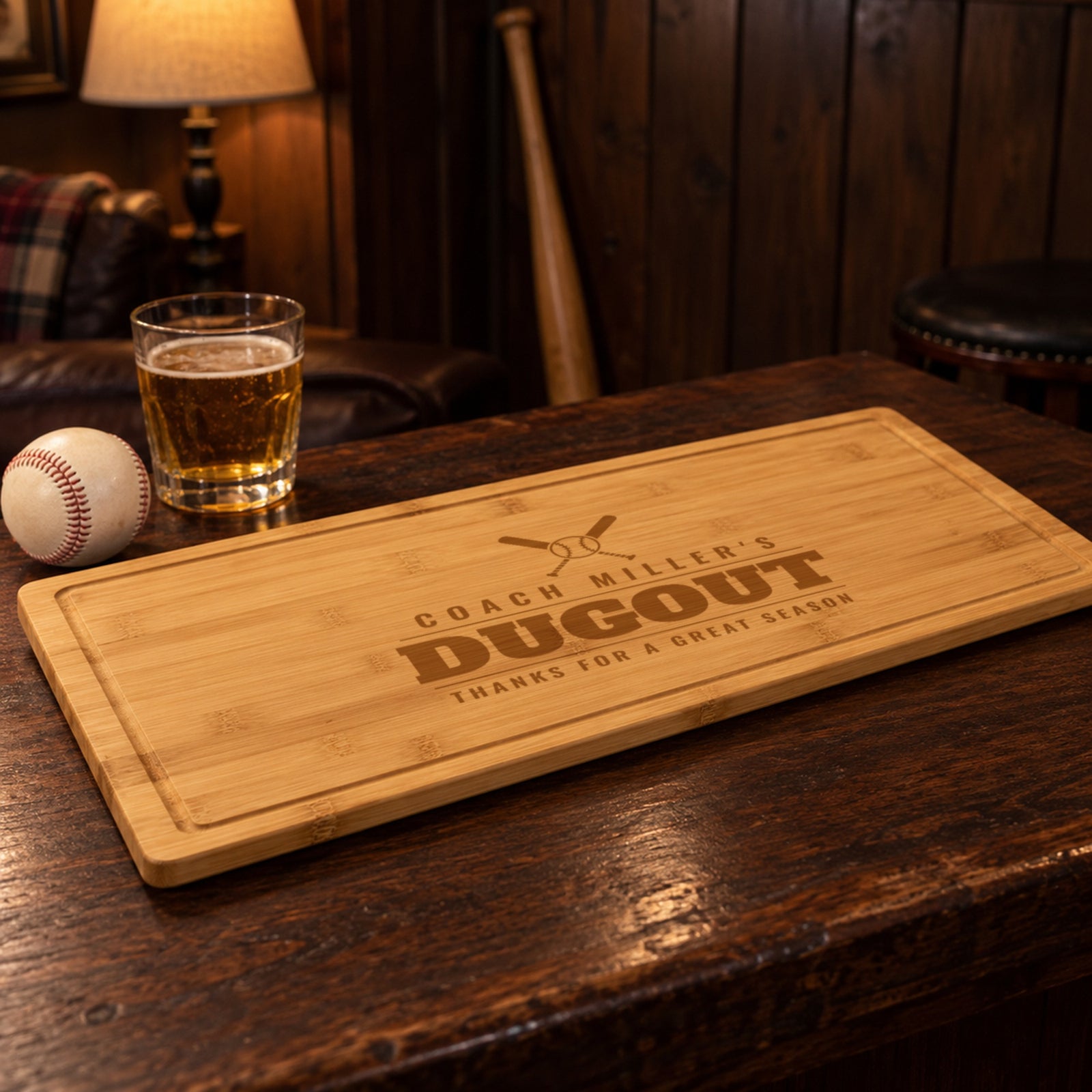 Baseball coach gift: cutting board engraved COACH MILLER'S DUGOUT, THANKS FOR A GREAT SEASON, on a dark wood bar with a baseball and a bat