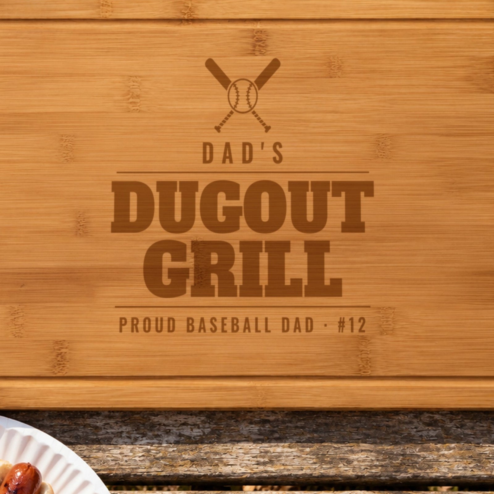 Close-up of the laser engraving on the baseball dad cutting board: crossed bats and a baseball over DAD'S DUGOUT GRILL burned into the bamboo