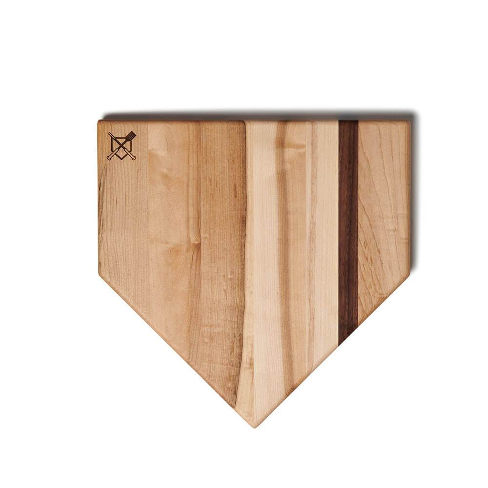 Home plate shaped cutting board in light wood with dark walnut accent stripe down the center, viewed from above at an angle