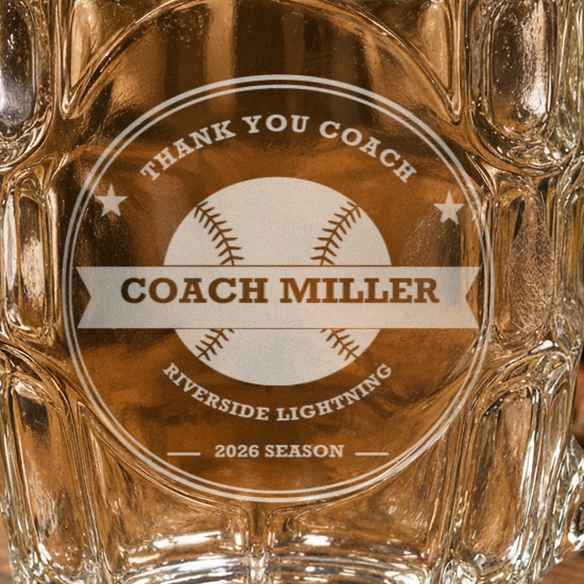 Close-up of the frosted laser engraving on the softball coach stein, showing the stitched softball, the Coach Miller banner and the team name arc