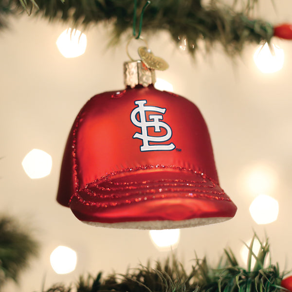 Red Cardinals baseball cap ornament with team logo hanging from evergreen garland with white lights