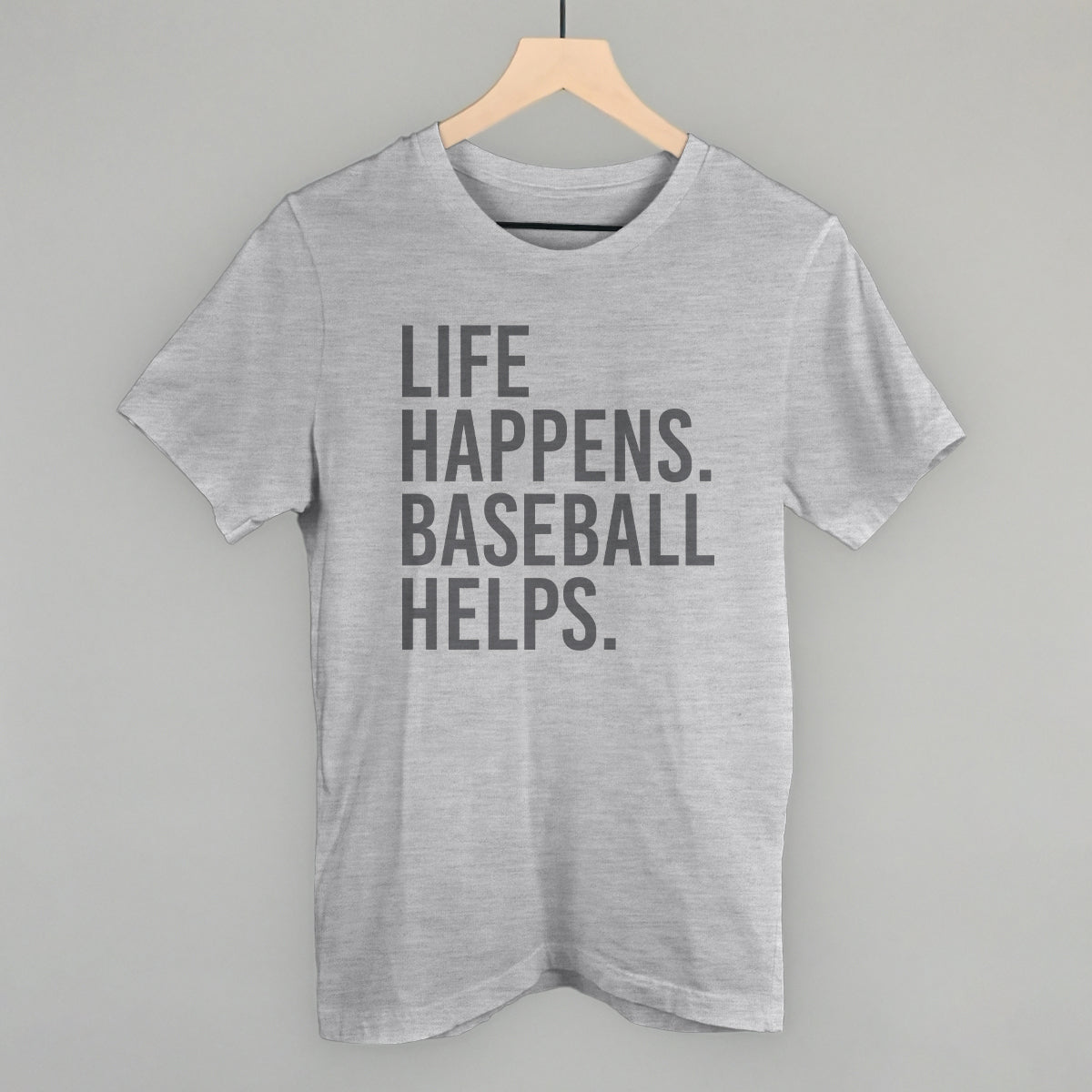 Light gray heather t-shirt with centered gray text reading "LIFE HAPPENS. BASEBALL HELPS.