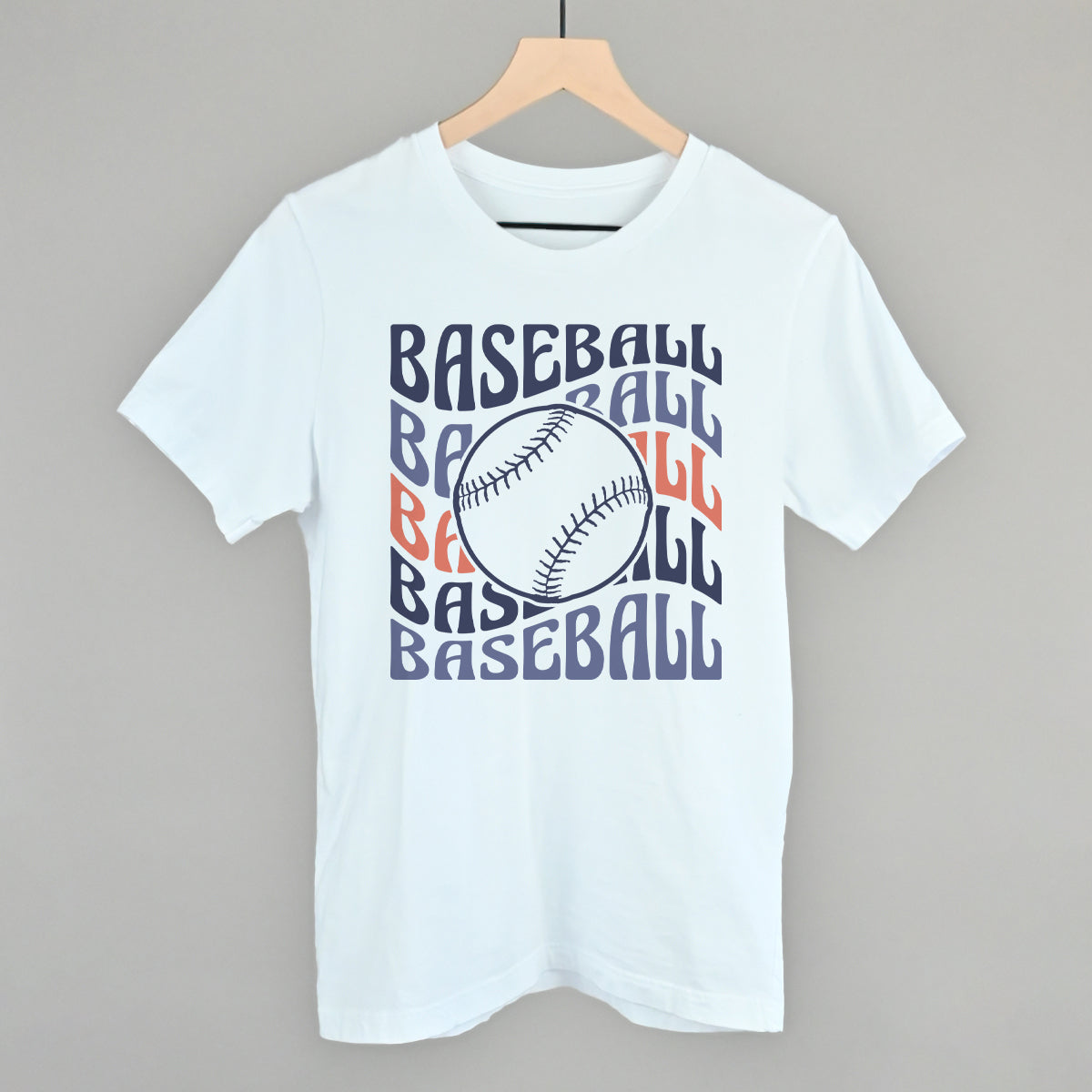 White Bella+Canvas tee with the Baseball Groovy Wave design in stacked retro lettering and a baseball center, printed in multi-color navy, lavender, and orange ink