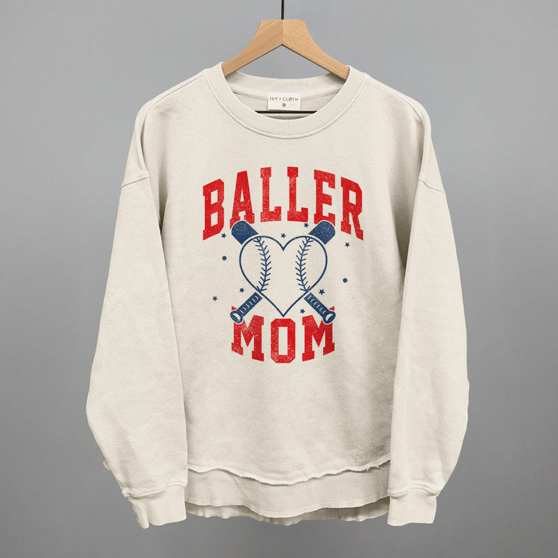 Tapioca cream crewneck sweatshirt with the Baller Mom design in red serif lettering and navy crossed bats around a baseball heart