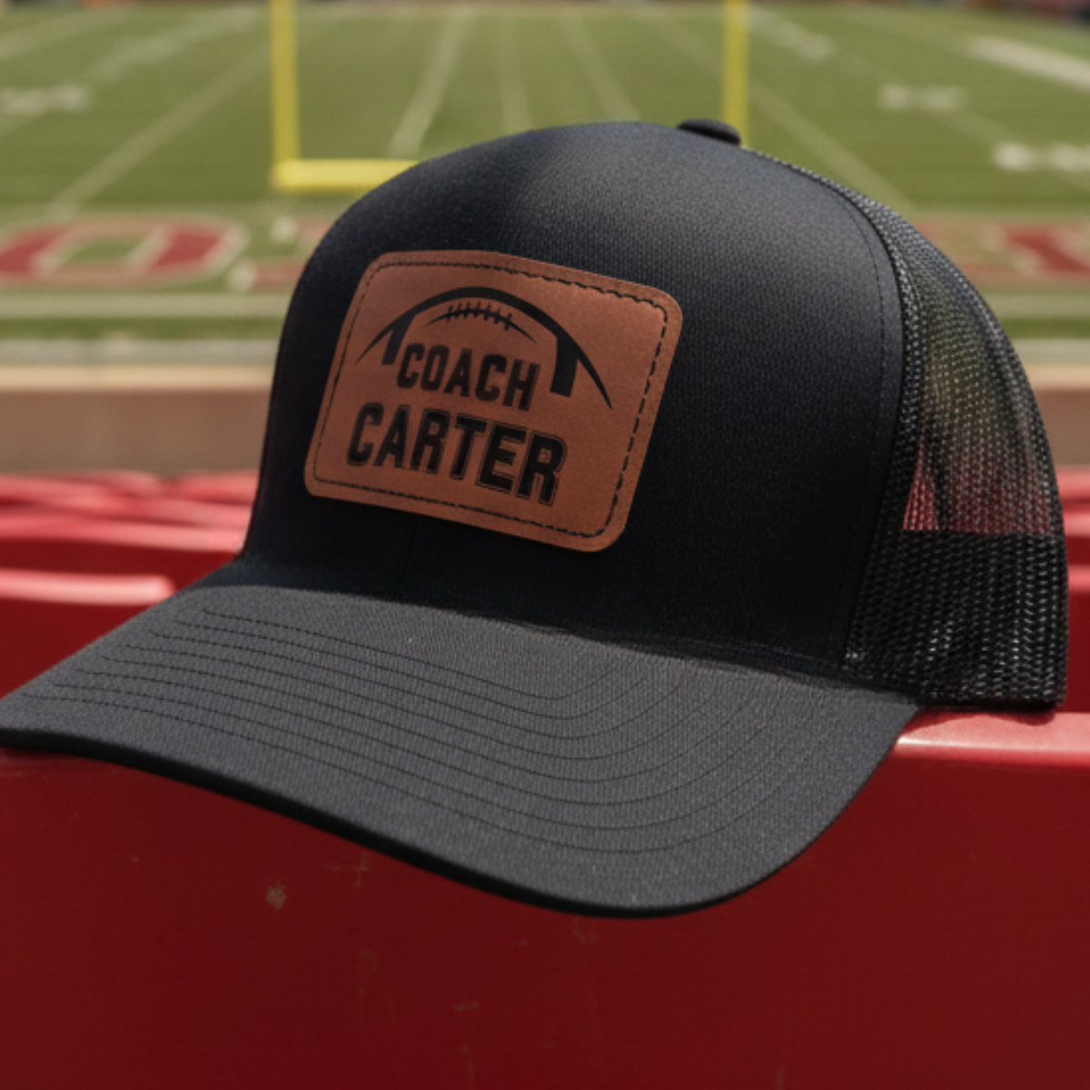Personalized football coach leather patch hat with a football and the coach's name laser-engraved into a real leather patch on a structured snapback cap