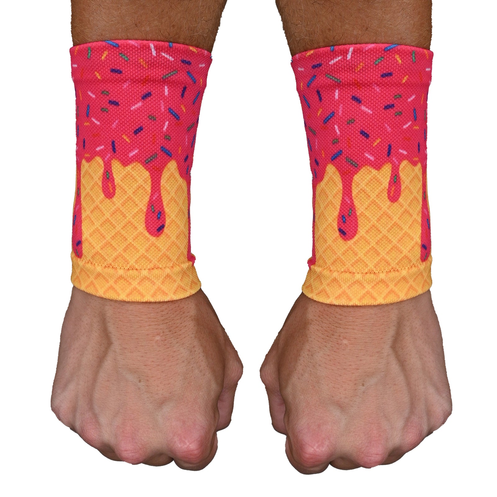 Pair of pink ice cream-patterned wrist support sleeves with yellow waffle cone design worn on model's wrists, showing compression fit and colorful sprinkle details.