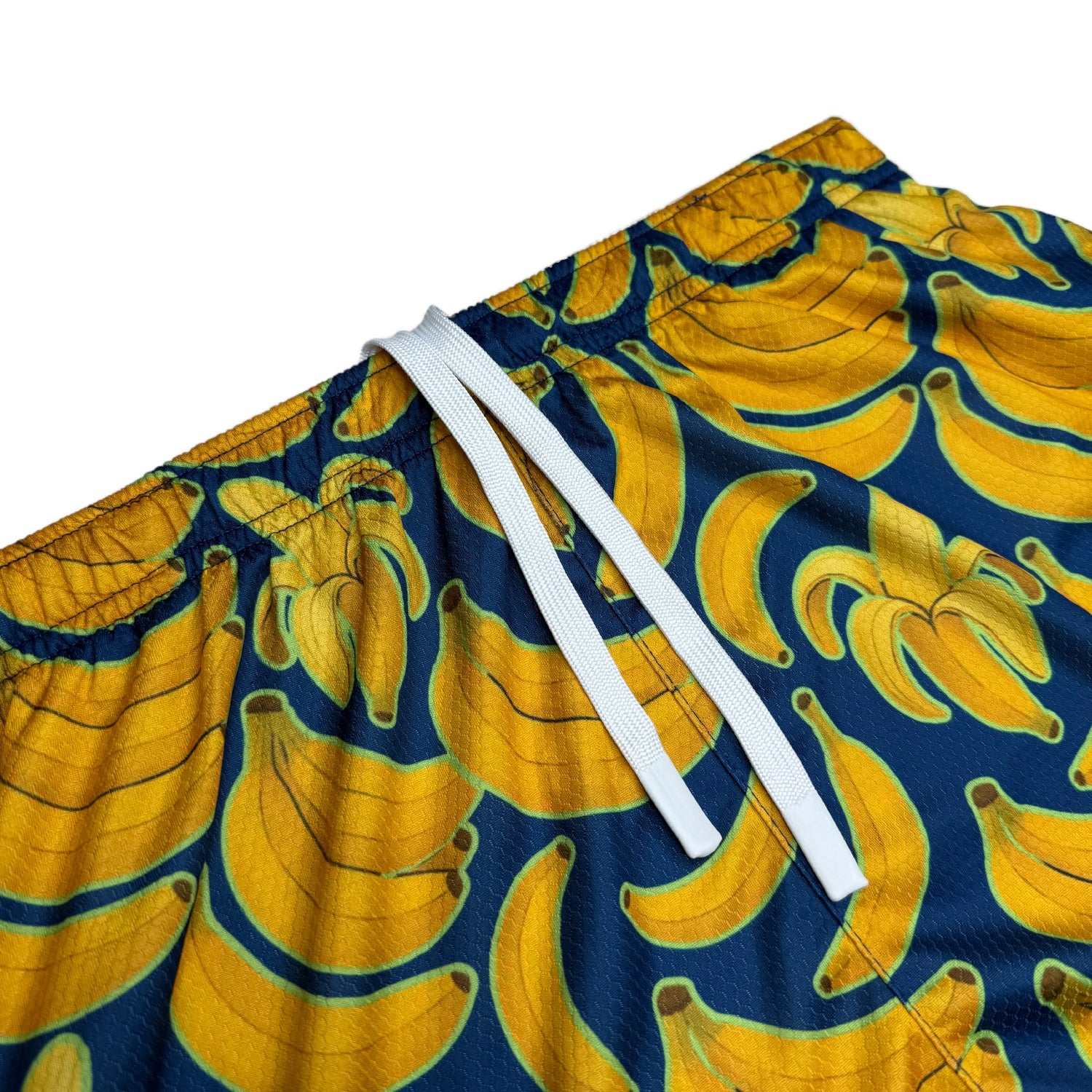 Close-up of the Banana Bunch shorts white drawstring waistband above the yellow banana print on navy mesh