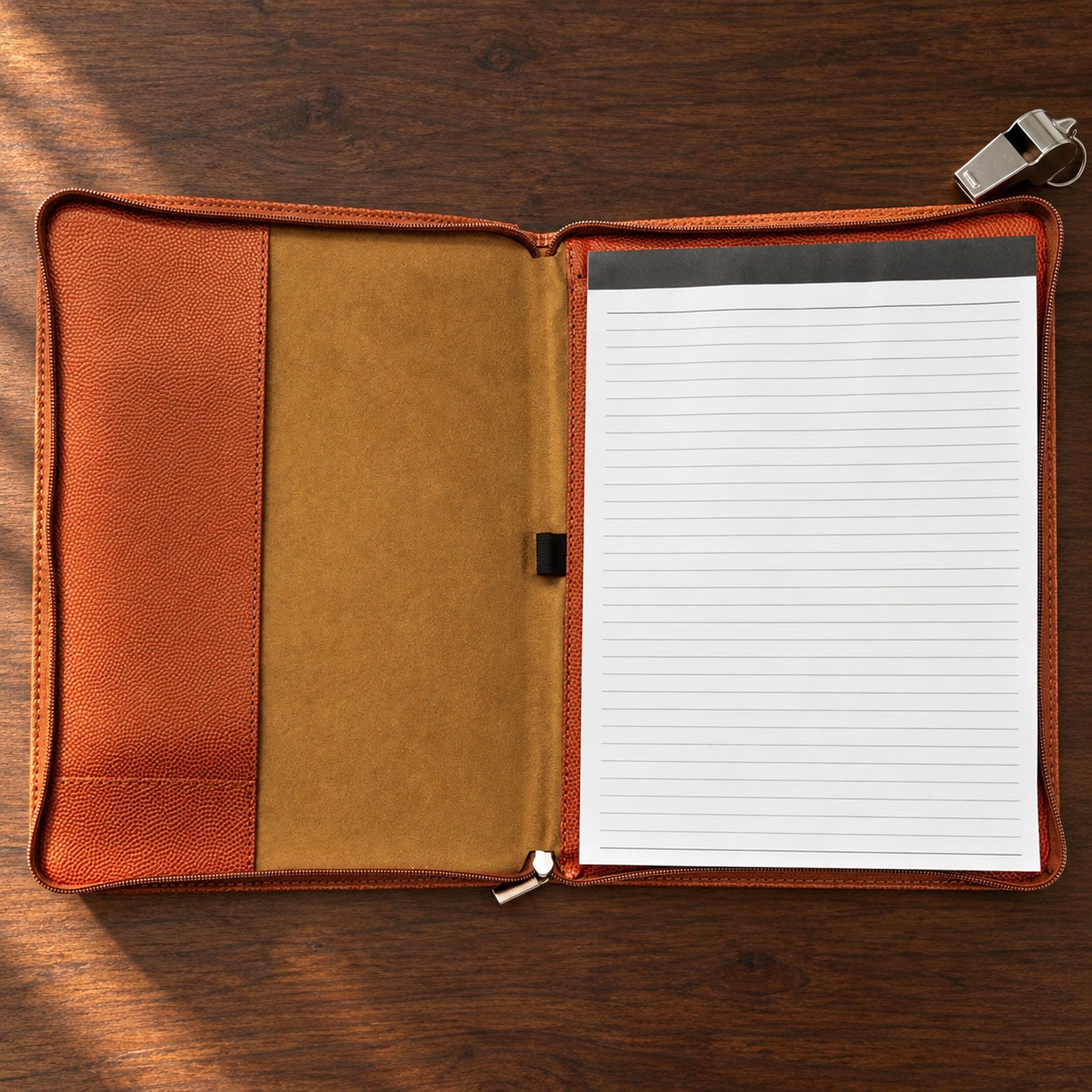 The basketball coach portfolio open on a desk, showing the lined legal pad, the empty pen loop and the tall inside pocket for rosters and practice plans
