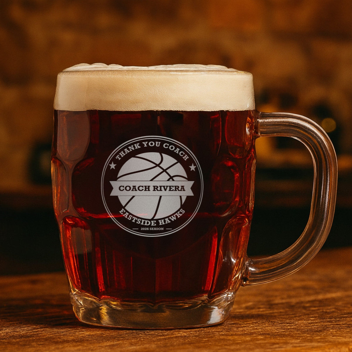 Engraved basketball coach stein with dark amber ale reading Thank You Coach, Coach Rivera and Eastside Hawks, showing the top line can be changed