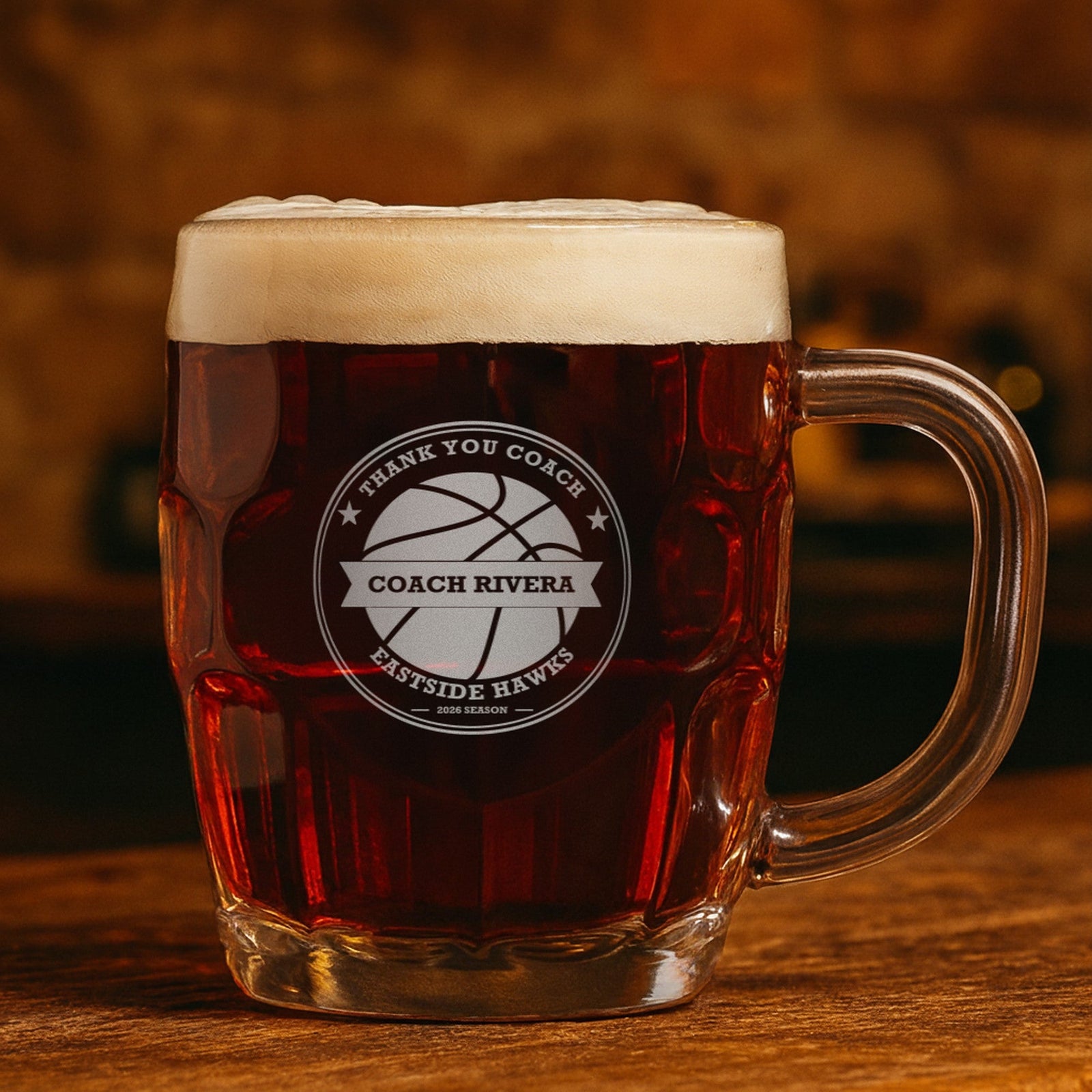 Engraved basketball coach stein with dark amber ale reading Thank You Coach, Coach Rivera and Eastside Hawks, showing the top line can be changed