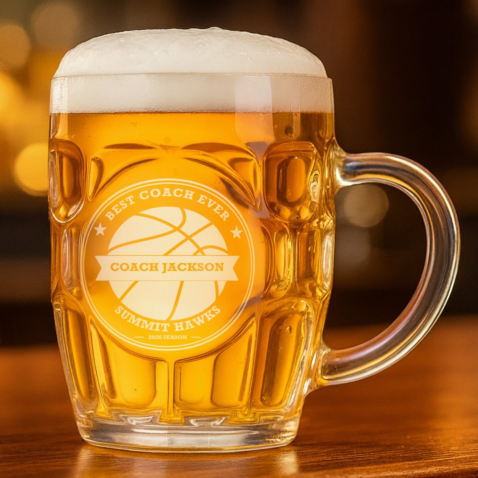 Basketball coach beer stein filled with golden lager, engraved Best Coach Ever with Coach Jackson across the banner and Summit Hawks below the ball