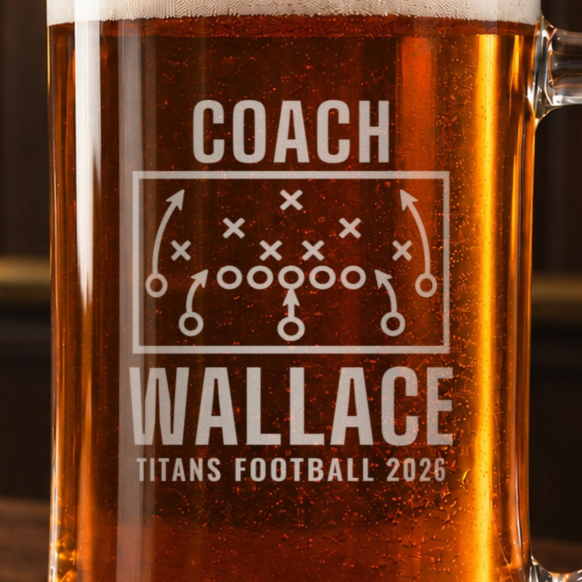Close-up of the frosted play diagram engraved on the football coach stein, X's, O's and route arrows above COACH, WALLACE and TITANS FOOTBALL 2026