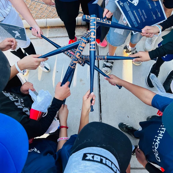 Team of kids holding up navy personalized mini bats outdoors to form a star pattern after a youth baseball event