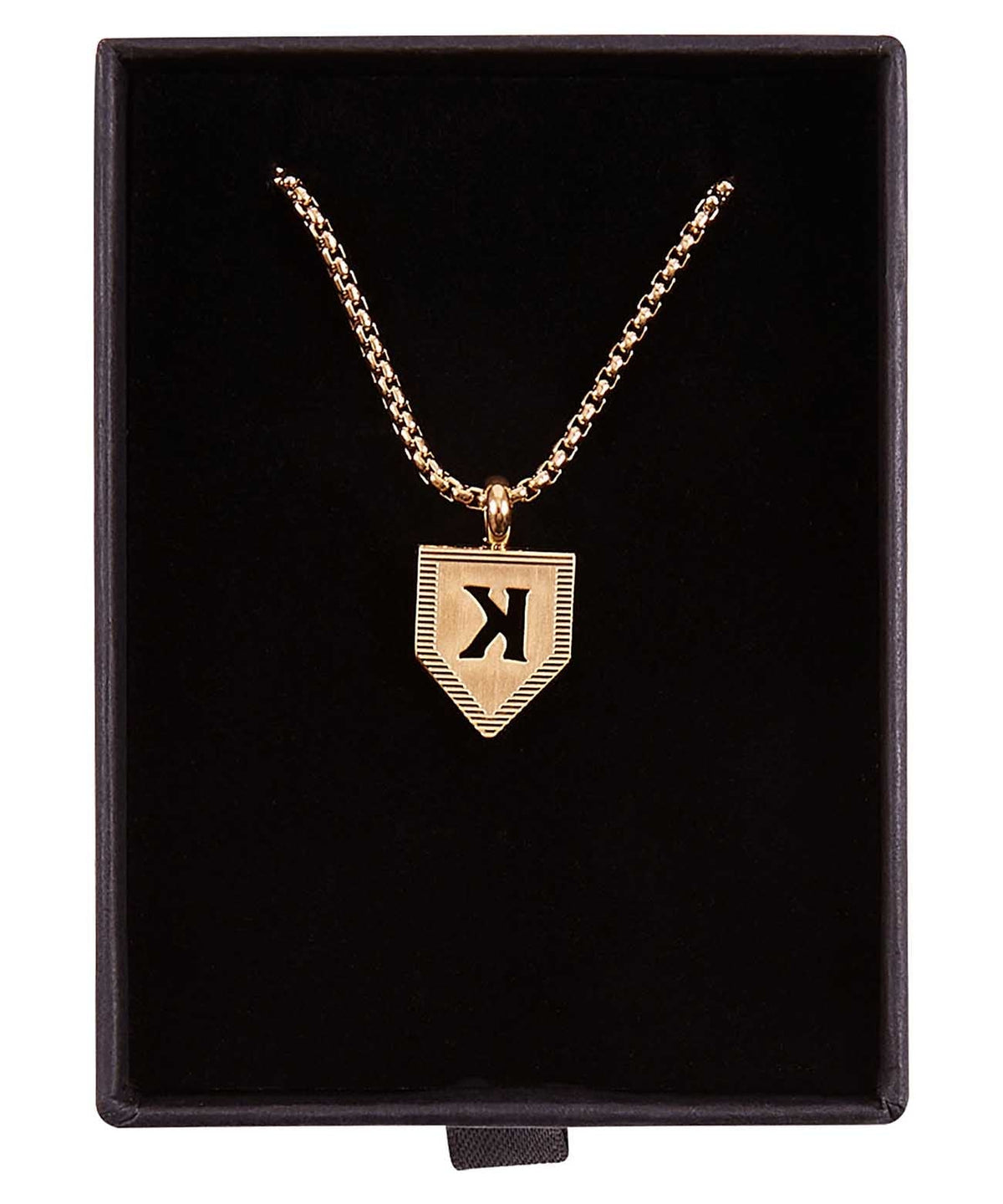 Gold-plated pendant necklace with sample letter K engraved on shield-shaped charm, displayed in black velvet box with rope chain.
