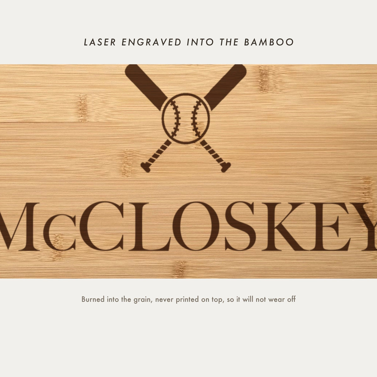 Close view of the crossed baseball bats and stitched ball laser engraved into the bamboo grain above the name in a high contrast serif.