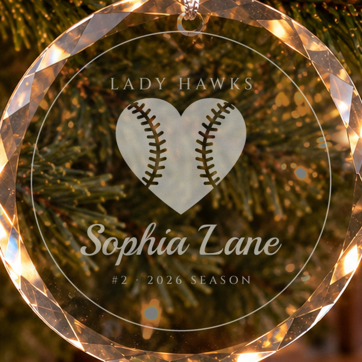 Close-up of the frosted engraving on the softball ornament: a softball heart with stitched seams, LADY HAWKS, Sophia Lane, #2 · 2026 SEASON