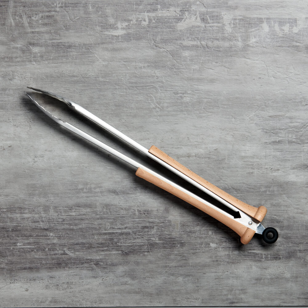 Top-down view of the closed splitfinger tongs angled across a grey concrete surface with the bat knob and lanyard tie visible
